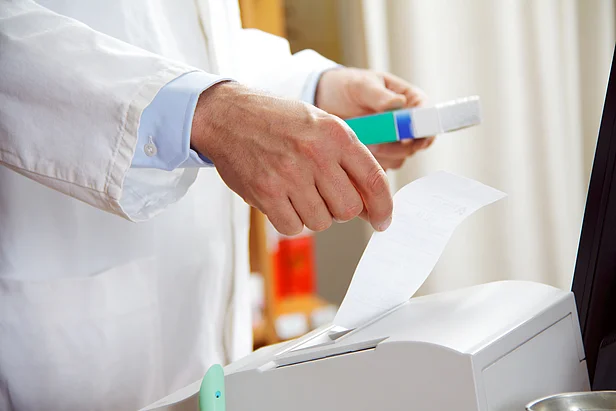 Hände eines Apothekers mit Medikament und Rechnung in der Hand